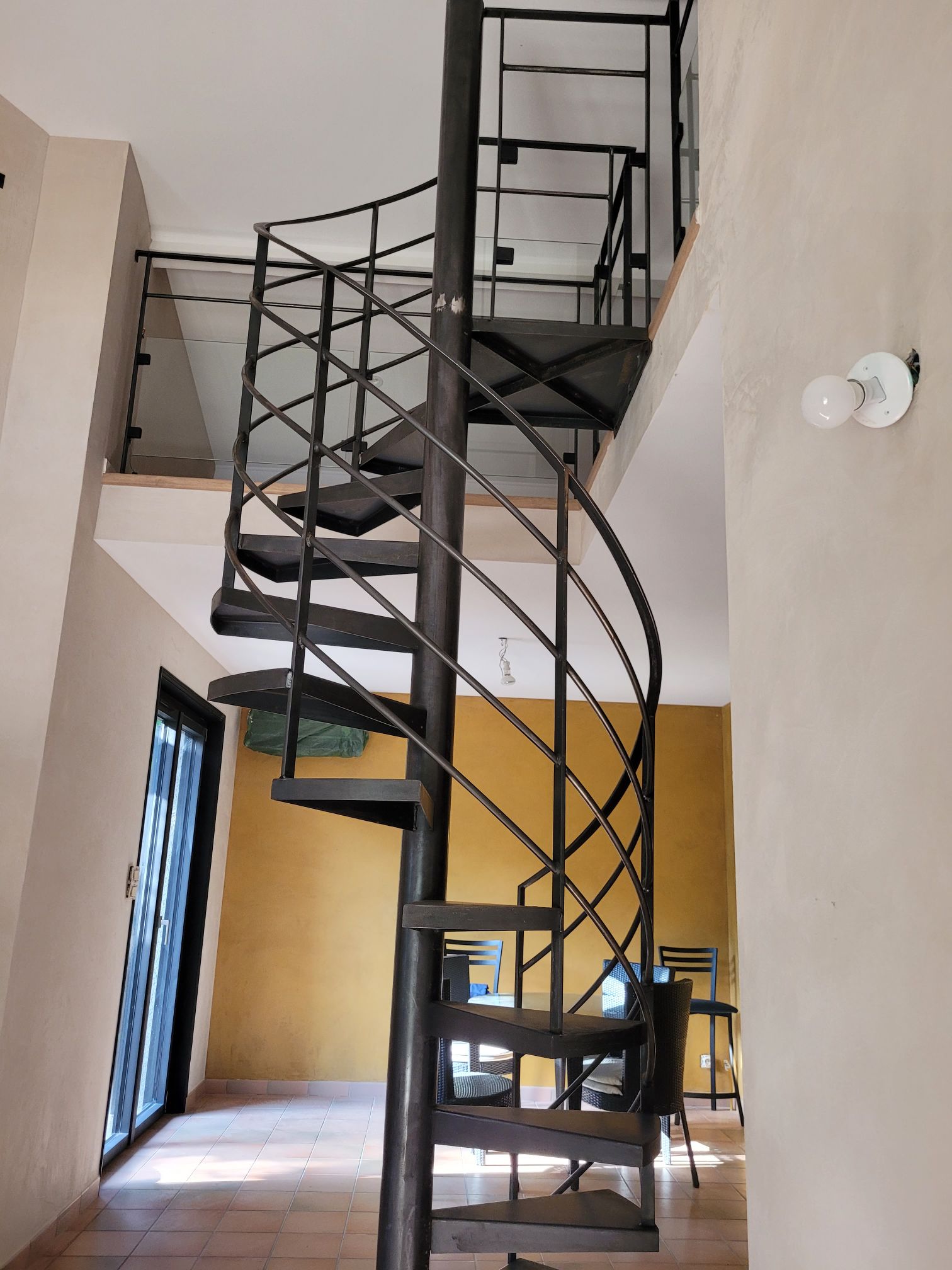 fabrication et pose d'un escalier hélicoïdal sur mesure en acier a Brignais proche de Lyon avec garde-corps métal verre le tout en finition patine cirée réalisation Métallerie RPA