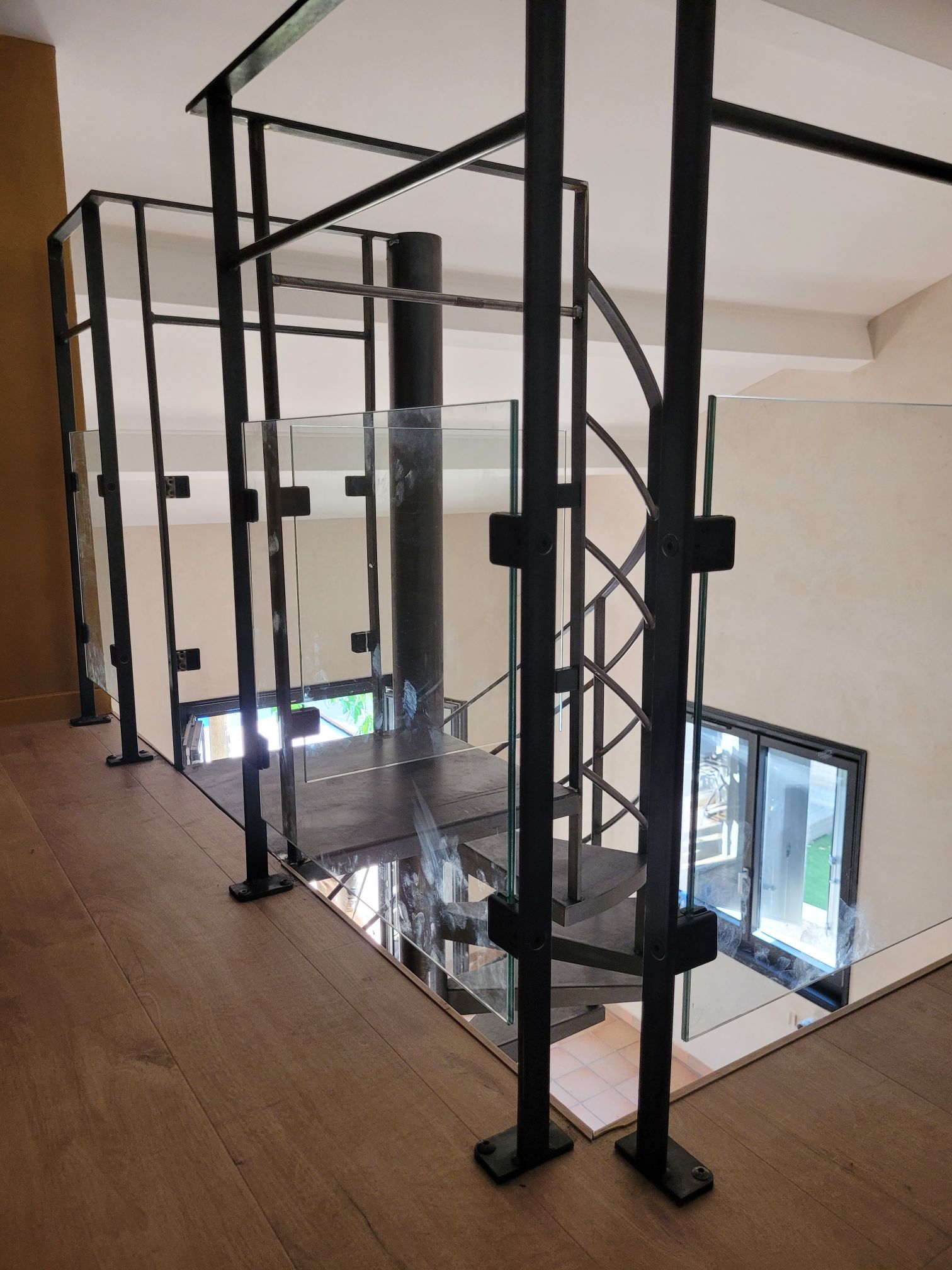 fabrication et pose d'un escalier hélicoïdal sur mesure en acier a Brignais proche de Lyon avec garde-corps métal verre le tout en finition patine cirée
